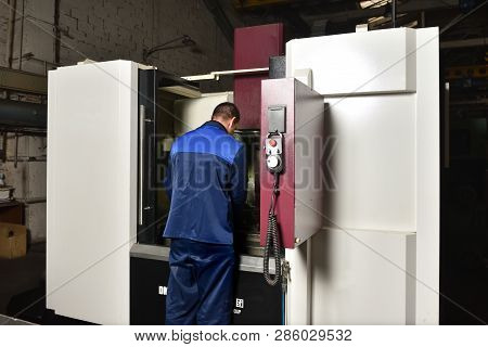 The Worker In Blue Workwear, The Operator Of The Cnc Machine, Oversees The Process And Controls It. 