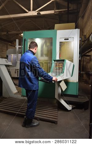 The Worker In Blue Workwear, The Operator Of The Cnc Machine, Oversees The Process And Controls It. 
