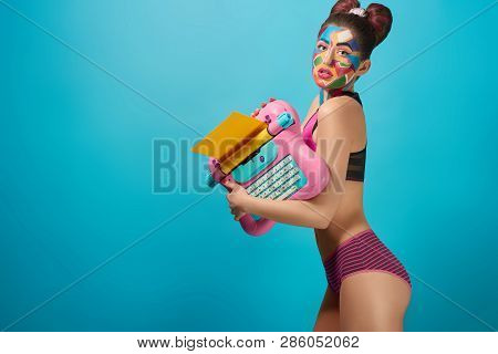 Skittish Girl Holding Pink Toy Typewriter, Looking At Camera With Seductive Look, Opened Mouth. Attr