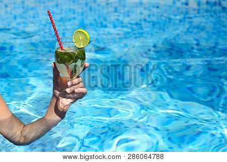 Hand Of The Woman Holding Glass Of Ojito In The Pool. Close Up