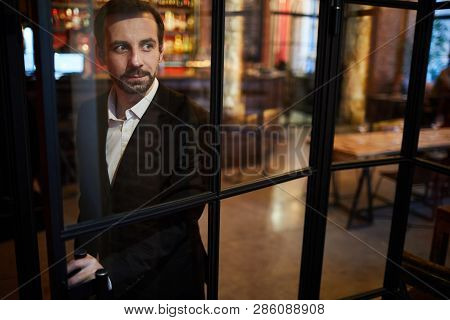 Portrait Of Handsome Mature Gentlemen Opening Glass Door In Cafe, Copy Space