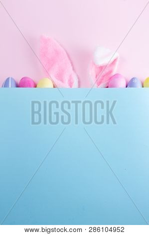 Easter Rabbit Flaffy Ears And Colored Easter Colored Eggs, Top View On Pink And Blue Background With