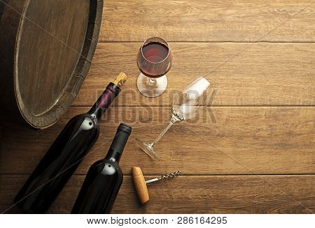 Glass And Bottle Of Red Wine With Wooden And Barrel Background