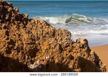 Rocks On The Clean Beach With Dark Yellow Sand. Foamy Waves Of The Atlantic Ocean. Horizon In The Ba
