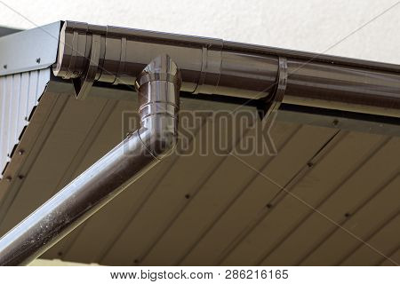 Close-up Detail Of Cottage House Corner With Brown Metal Planks Siding And Roof With Steel Gutter Ra