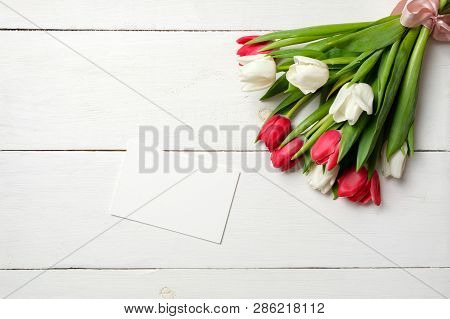 Blank Card For Invitation Or Congratulation With Bunch Of White Tulips Flowers On White Wooden Table