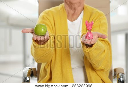 Senior Woman With Between Apple And Candy In Hospital, Closeup. Diabetes Diet