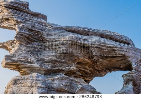 Closeup Of Large Geological Rock Formation With Visible Sedimentary Layers With Blue Sky In Backgrou