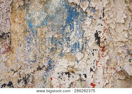 Old Blue Wall With Damage, Cracks And White Peeling Paint With Red And Black Spots. Rough Surface Te