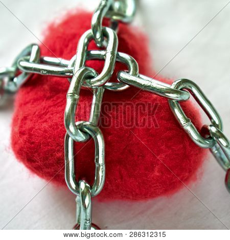 Red Wool Heart Locked With Metal Chain On White Bed Sheet
