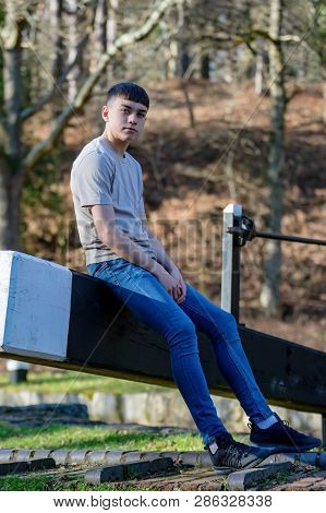 Portrait Of A Caucasian Teenage Boy On A Warm Spring Day Sitting On A Lock Gate