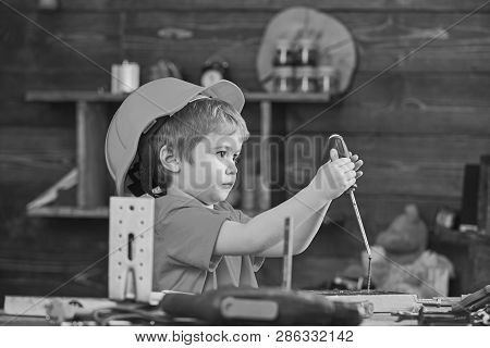 Side View Little Kid Binding Screw Into Wooden Board. Concentrated Boy Playing With Screwdriver. Lit
