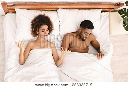 Sex Problem. Upset Black Lovers Lying On Bed, Woman Unsatisfied, Sad Man Looking Under Blanket, Top 