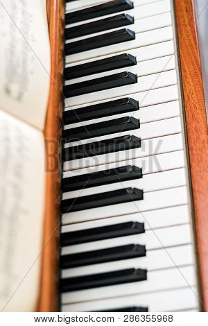 The Keyboard Of A Brown Upright Piano With Blurred Sh Eet Music. Selective Focus.