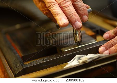 Closeup Of Ink-stained Fingers Of Man Using A Quoin Key To Prepare Type For Letterpress Printing