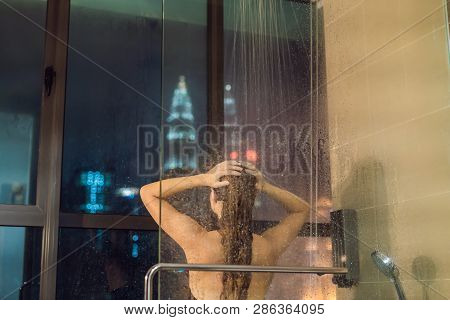 Beautiful Woman In The Shower Behind Glass With Drops On The Background Of A Window With A Panoramic