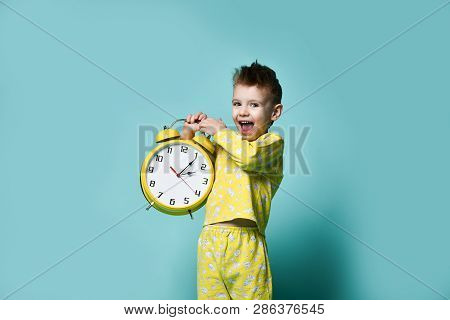 Cute Little Boy With Alarm Clock,isolated On Blue. Funny Kid Shouting Joyfully Pointing At Alarm Clo