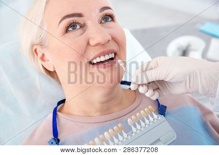Dentist Selecting Patient's Teeth Color With Palette In Clinic