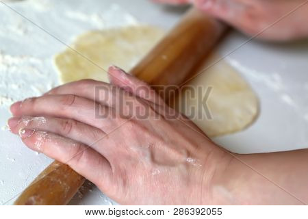 Woman Rolls Out The Dough On The Table With A Rolling Pin, Female Hands Soiled In Flour Close-up. Co