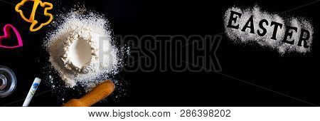 Handrful Of Sieved Flour With Egg Shape Hole In The Center And Utensils For Baking Around And Latter