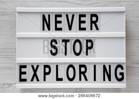 'never Stop Exploring' Word On Modern Board Over White Wooden Background, Top View. Overhead, Flat L