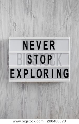 Lightbox With Text 'never Stop Exploring' Over White Wooden Surface, Top View. Overhead, Flat Lay, F
