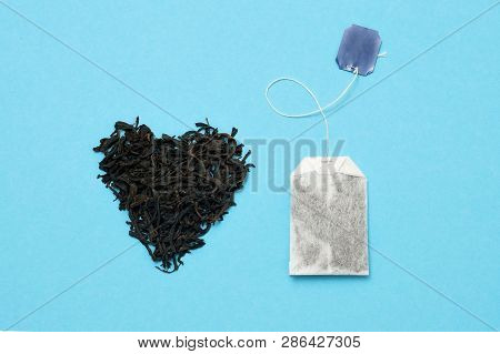 Tea Bag And Black Leaves On Blue Background. What Kind Of Tea Is Better