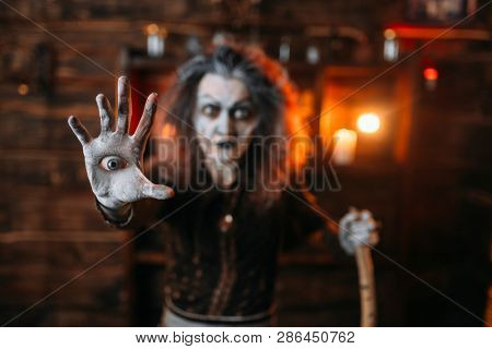 Scary witch with an eye in the palm, seance