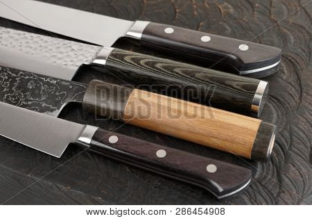 Knife handles and blades on black cutting board, close-up