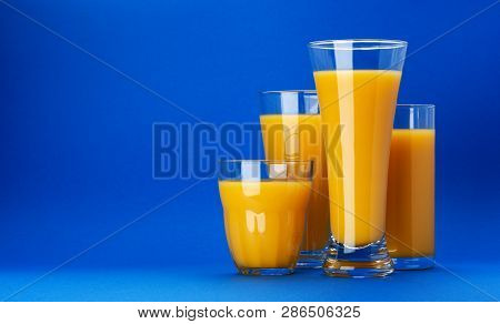 Glasses Of Orange Juice On Blue Background With Copy Space