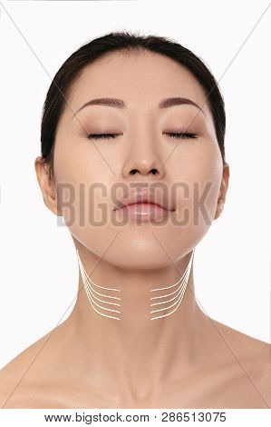 Asian Woman With Arrows On Her Face Over White Background. Neck Lifting Concept. Correction Of Doubl