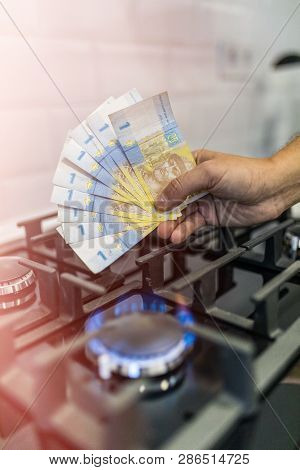 Cooktop With Burning Gas Ring With Hands Holding Money 9 Uah Hryvnas For Combustion At Home.