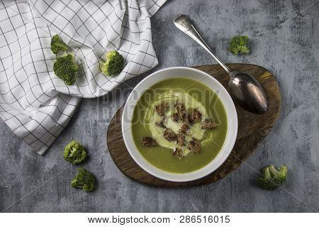 Top View Of Served Brocoli Creamy Soup With Cream And Bread Croutons On Rustic Table With Spoon And 
