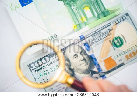 Hundred Dollar Under A Magnifying Glass On The Bacdrop Euro And Ruble Banknotes. Сoncept Of The Main