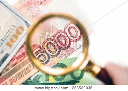 Five Thousand Russian Rubles  Under A Magnifying Glass On The Bacdrop Euro And Usa Dollar. Сoncept O