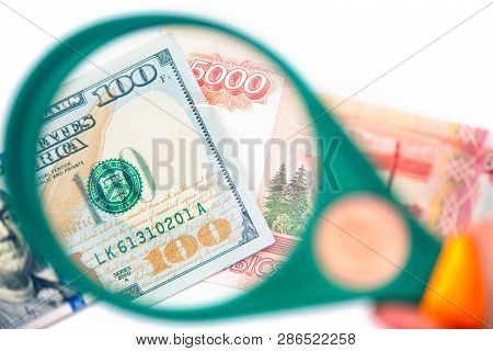 Hundred Dollar Under A Magnifying Glass On The Bacdrop Euro And Ruble Banknotes. Сoncept Of The Main