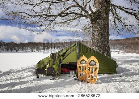 tent, backpack and snowshoes in winter landscape of Nebrodi Park, Sicily