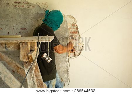Worker Removing The Plastered Cement Surface On The Bricklayer Wall