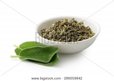 Dried Rubbed Sage In A White Ceramic Bowl Next To Fresh Sage Leaves Isolated On White.