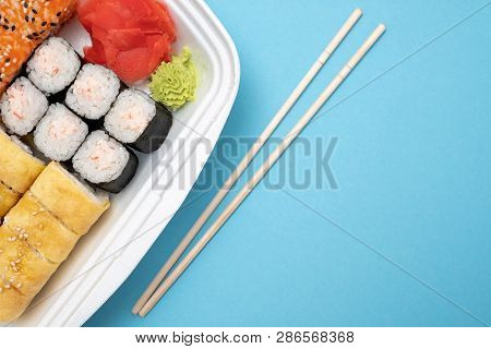 Top View On Sushi Set At Colored Background. Plate With Rolls, Ginger And Vasabi