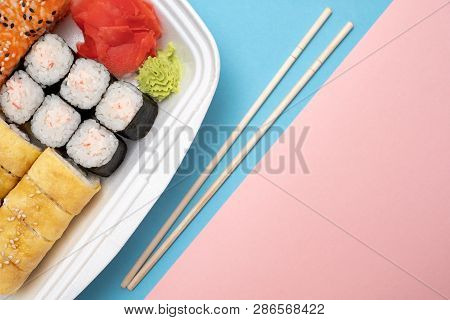 Top View On Sushi Set At Colored Background. Plate With Rolls, Ginger And Vasabi