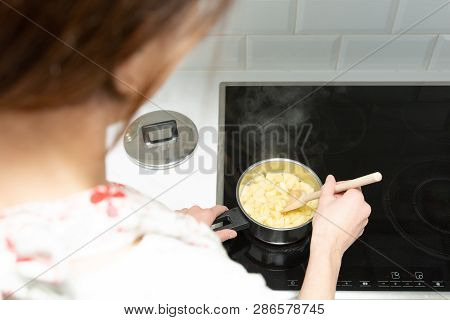 Supermom Preparing Dinner For A Baby In A White Modern Kitchen