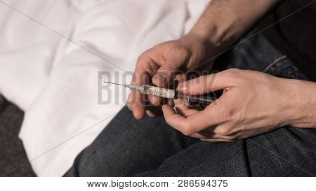 Selective Focus Of Narcomaniac Man Holding Syringe With Dose Of Heroin