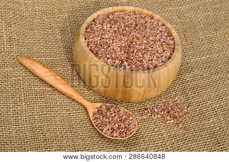 Uzbek Devzira, The Red Rice In A Bamboo Bowl And In Wooden Spoon On Burlap