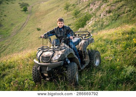 The Boy Is Traveling On An Atv.