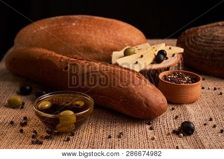 Fresh Bread Baguette With Olive Oil, Olives. Cheese And Rosemary On Wooden Background. Teasty Breakf