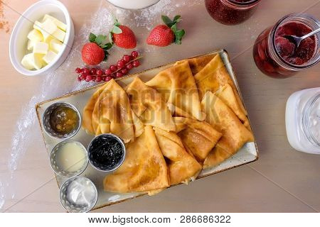 Russian Traditional Pancakes, Blini Served With Jams, Sour Cream, And Strawberry On The Plate. Close
