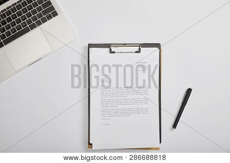 Top View Of Documet On Clipboard, Pen, Laptop On Table