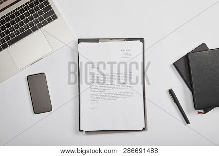 Top View Of Documet On Clipboard, Smartphone, Pen, Laptop And Notebooks
