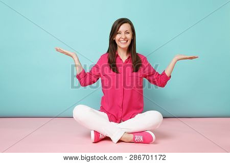 Full Length Portrait Of Smiling Young Woman In Rose Shirt Blouse, White Pants Sitting On Floor Isola